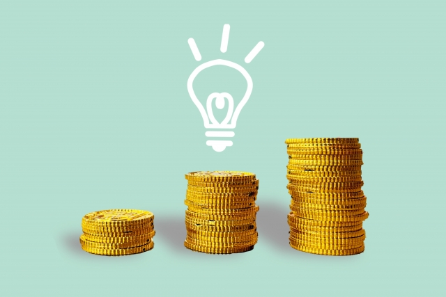 青背景に積み上がる金貨と電球